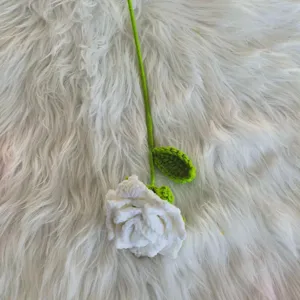 Handmade crochet white rose detail, delicate yarn knitting flower with green stem and leaf.