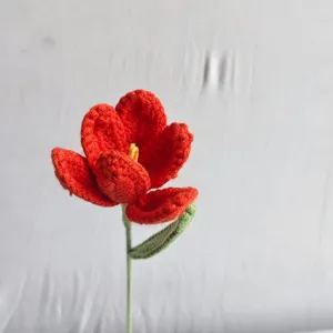 Handmade crochet red tulip flower detail shot, delicate yarn texture and stem design.
