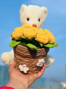 Handmade crochet white bear holding yellow flower bouquet in woven pot detail view.