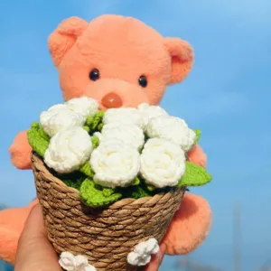 Handmade crochet bear with white flower bouquet in woven basket, cute gift ornament.