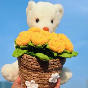 Handmade knitted bear holding yellow crochet flower bouquet detail shot, perfect gift ornament.