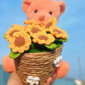Detail view of handmade knitted crochet bear holding cute sunflower potted plant decor.