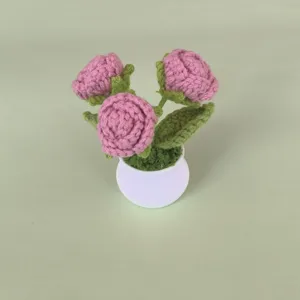 Handmade crochet pink rose potted plant, intricate yarn knit flower detail for desktop decor.