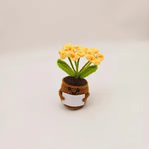 Handmade crochet potted plant with yellow flowers, green leaves, and cute smiling pot.