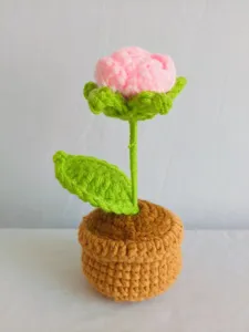 Handmade crochet pink rose flower pot detail view, cute yarn plant decor for desktop display.