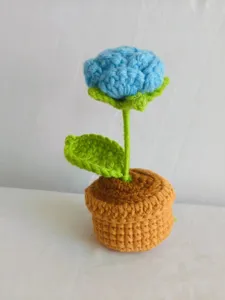 Handmade crochet potted flower detail shot, knitted blue rose plant desk decoration.