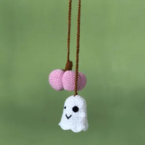 Vue détaillée de porte-clés citrouille fantôme au crochet fait main, charmant accessoire Halloween.