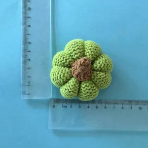 Detailed view of handmade crochet green pumpkin decoration with clear size rulers for measurement.