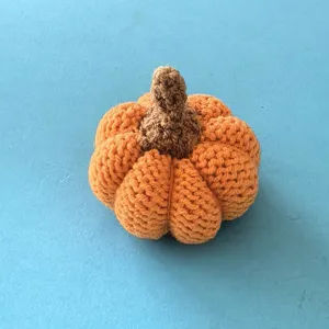 Handmade crochet pumpkin ornament detail view, orange knitted yarn plush decor gift item.