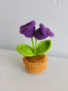 Handmade crochet purple flower potted plant detail, cute wool knit home decor ornament.