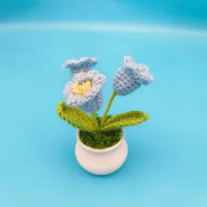Handmade crochet blue bellflower potted plant detail, cute yarn flower desktop decor.