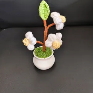 Handmade crochet flower potted plant detail showing cute puff flowers and white pot.