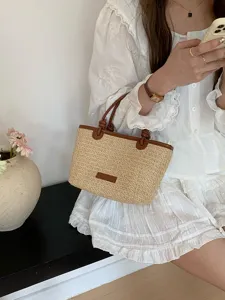 Detailaufnahme einer schicken Strohhandtasche mit kontrastierenden PU-Leder-Akzenten.