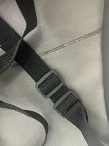 Détail de sangle et boucle en nylon noir réglable sur filet de protection de ventre de cheval.