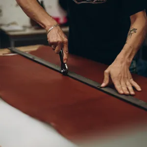 Detailed shot of genuine leather crafting process, showing premium brown leather sheet cutting.