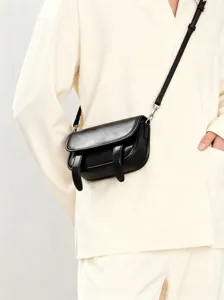 Detailopname van zwarte mini crossbodytas gedragen door model, glad leer en riem.
