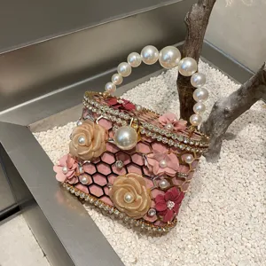 Vista dettagliata della lussuosa borsa da sera rosa con manico di perle e strass brillanti.
