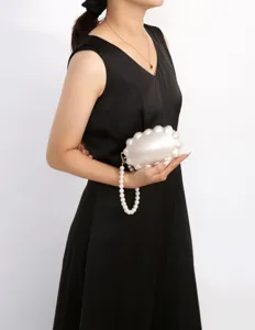 Detailed view of white pearl shell evening clutch bag with elegant wrist strap, acrylic material.
