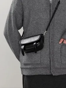 Close-up detailweergave van een stijlvolle zwarte lederen mini crossbody tas gedragen.