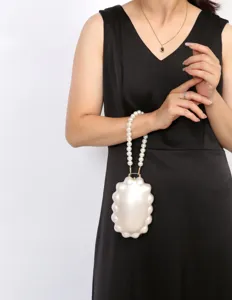 Detail shot of pearl strap evening bag, elegant shell clutch accessory for women's daily use.