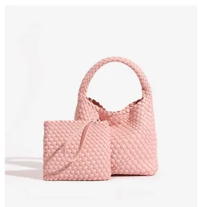 Detailed view of the pink woven leather handbag and matching pouch set elegantly.