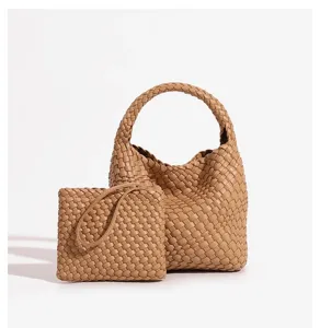 Detailed view of the woven leather handbag and matching pouch set in camel color.