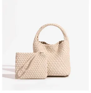 Detailed shot of beige woven leather handbag and matching clutch set, elegant and stylish.