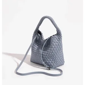 Light blue woven leather bucket bag detail, showcasing intricate handcrafted pattern and strap.