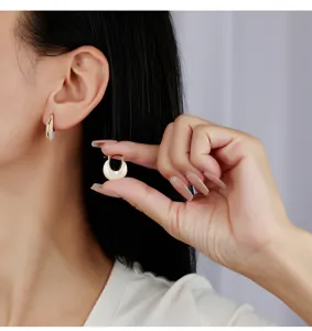 Détail de boucles d'oreilles créoles U en nacre double face style français élégant.