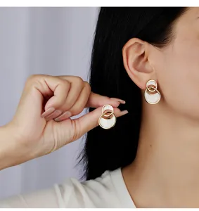 Primer plano detallado de pendientes de doble anillo con esmalte blanco y oro.