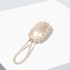 Detailed view of the elegant pearl handle evening clutch, showcasing the glossy acrylic texture.