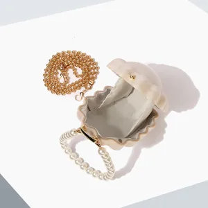 Detail view of pearl handle shell evening bag, elegant clutch purse with metal chain.