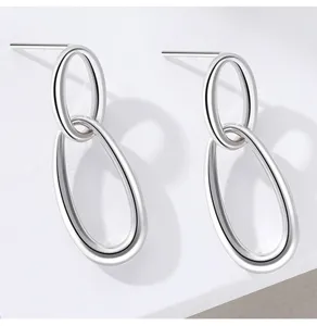 Detailweergave van minimalistische zilveren geometrische dubbele oorknopjes voor dames.