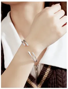 Primer plano de una pulsera de metal plateado abierta y elegante con detalles de pedrería.