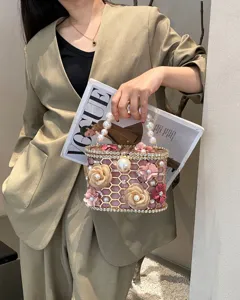 Primo piano dettagliato della borsa da sera con struttura a nido d'ape, perle e fiori.