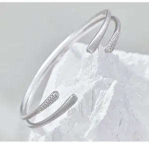 Detalle de primer plano de pulsera brazalete abierta doble con extremos de circón y mate.