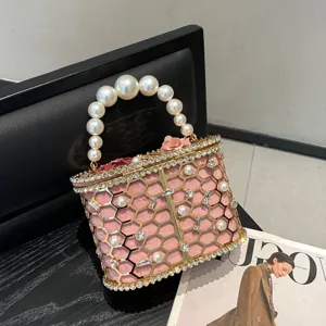 Vista dettagliata della borsa di lusso rosa con perle, strass e struttura in metallo.