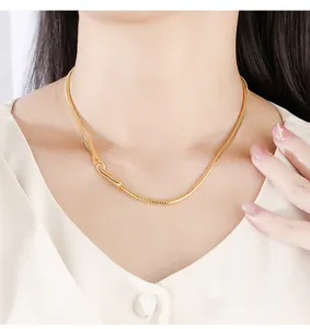 Minimalist gold snake bone chain detail close up view showing smooth metal texture.