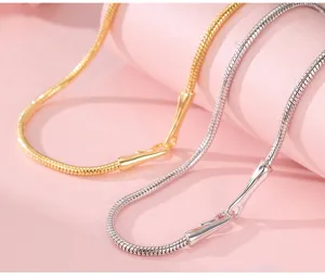 Close-up detail of minimalist gold and silver snake bone necklaces, showcasing sleek metallic texture.
