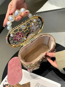 Borsa da sera rigida in metallo con strass manico di perle e design traforato da donna.