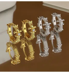 Gros plan de boucles d'oreilles créoles argentées et dorées avec un design de croix classique.