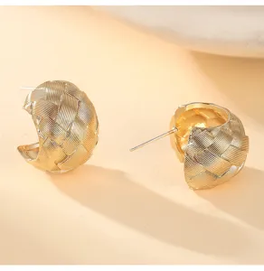 Detailed view of textured woven gold C-hoop earrings, chic French style fashion jewelry.
