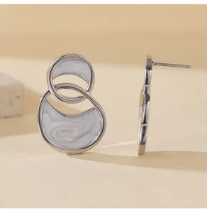 Primer plano detallado de pendientes asimétricos de doble aro esmaltado con estilo francés.