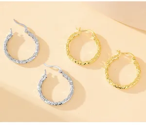 Gros plan detaille de boucles doreilles creoles texturees glacee en or et argent, style elegant.