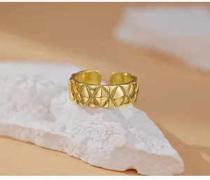 Detalle exquisito de anillo acolchado dorado, diseño abierto con clásico patrón de rombos.