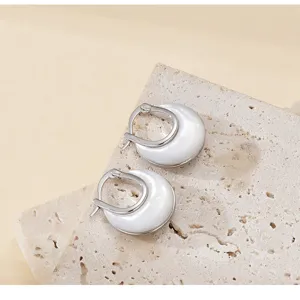 Vue détaillée de boucles d'oreilles nacrées argentées élégantes sur un support pierre chic.