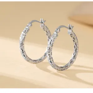 Gros plan de boucles d'oreilles créoles en argent sterling S925 à texture de surface effet givré.