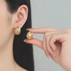Gold woven textured C-hoop earrings worn and held by model, elegant French style jewelry.