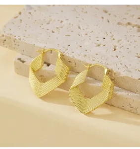 Detailansicht goldene gedrehte geometrische Creolen, einzigartiges geflochtenes Kupferschmuck.
