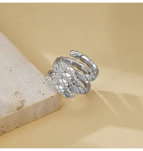 Anello argento con motivo rombo intrecciato in primo piano, dettaglio gioiello lusso.